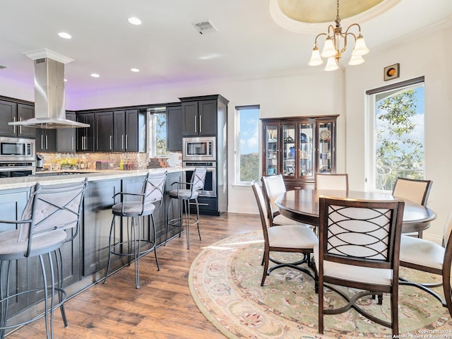 dining space with hardwood / wood-style floors, crown molding, and a notable chandelier