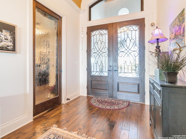 entrance foyer with french doors, dark hardwood / wood-style floors, crown molding, and a healthy amount of sunlight