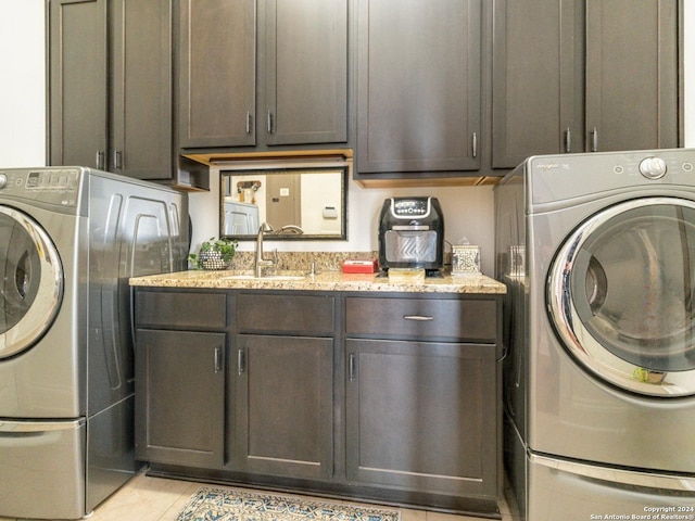 washroom featuring light tile patterned flooring, cabinets, sink, and washing machine and dryer