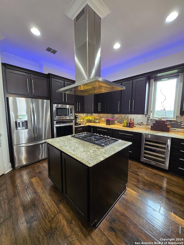 kitchen with dark hardwood / wood-style floors, appliances with stainless steel finishes, a kitchen island, island exhaust hood, and beverage cooler