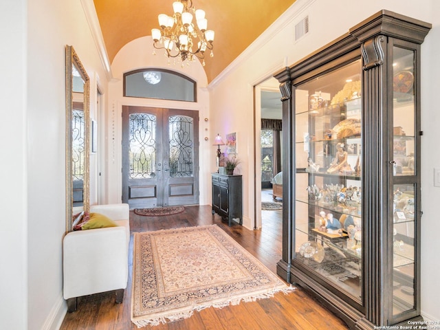 foyer with dark hardwood / wood-style flooring, french doors, vaulted ceiling, and a notable chandelier