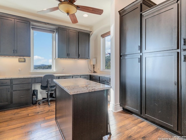 kitchen featuring a center island, hardwood / wood-style flooring, light stone counters, and plenty of natural light