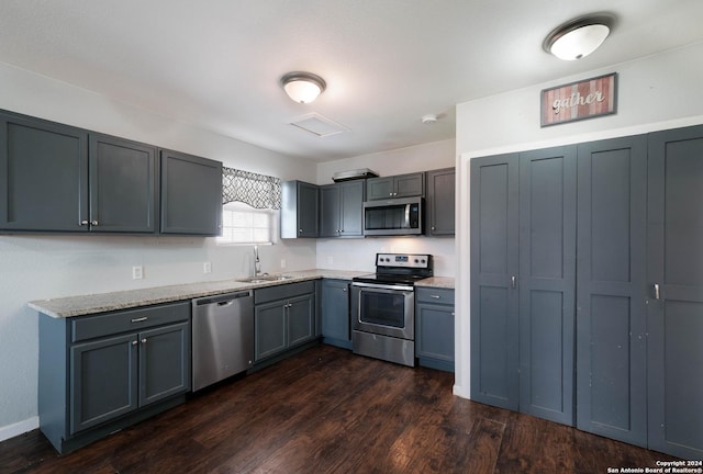 kitchen featuring appliances with stainless steel finishes, gray cabinets, dark wood-type flooring, and sink