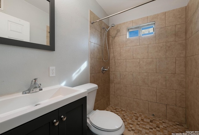 bathroom with vanity, toilet, and tiled shower