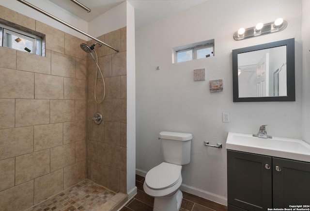 bathroom with tile patterned floors, vanity, toilet, and a tile shower