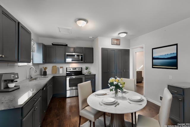 kitchen featuring dark wood-type flooring, sink, gray cabinets, light stone countertops, and stainless steel appliances