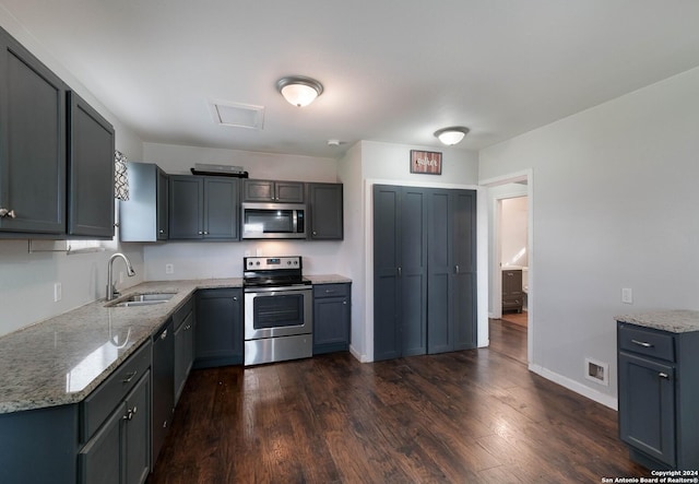 kitchen with gray cabinetry, light stone countertops, sink, dark wood-type flooring, and stainless steel appliances