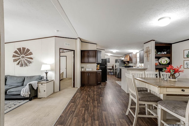 dining area featuring vaulted ceiling, ornamental molding, a textured ceiling, and hardwood / wood-style flooring