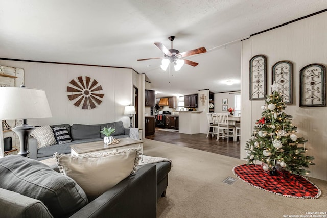 carpeted living room with ceiling fan and crown molding