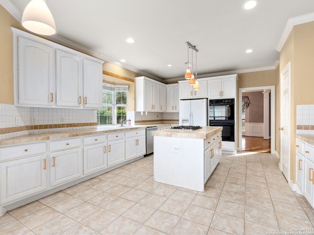 kitchen with white cabinets, appliances with stainless steel finishes, decorative light fixtures, and a kitchen island