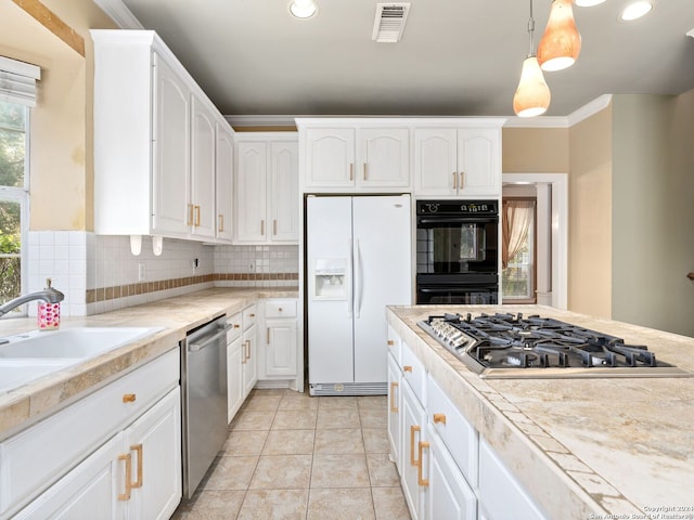 kitchen featuring appliances with stainless steel finishes, backsplash, sink, decorative light fixtures, and white cabinetry