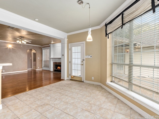 unfurnished living room with ceiling fan, light wood-type flooring, and crown molding