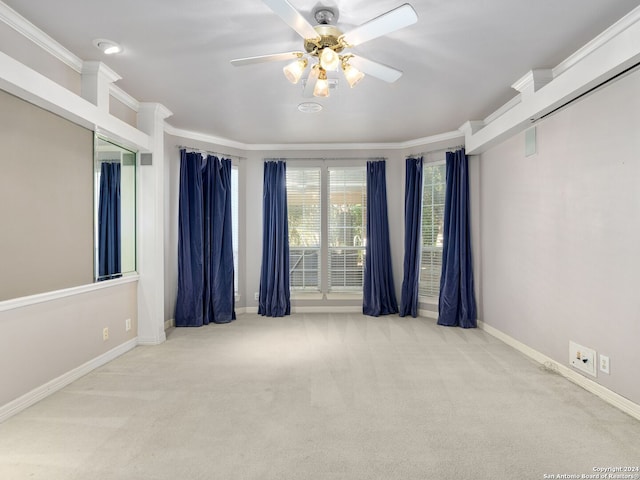 spare room with ceiling fan, crown molding, and light carpet