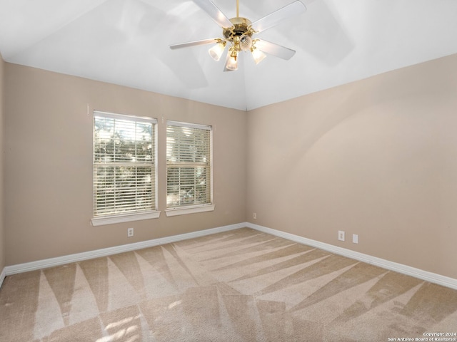 spare room featuring ceiling fan, light colored carpet, and lofted ceiling