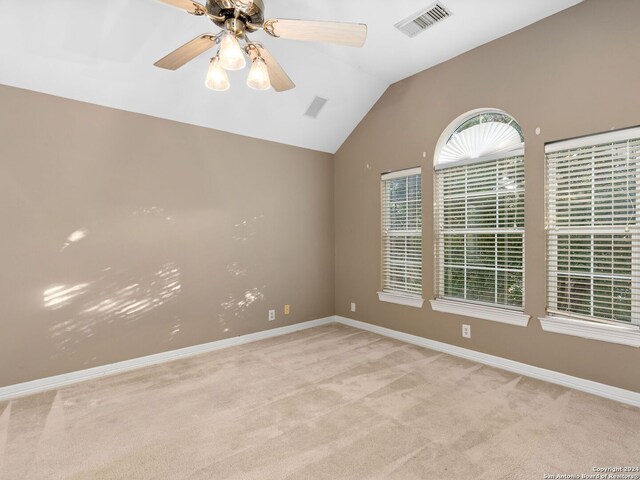 spare room featuring ceiling fan, lofted ceiling, and light carpet