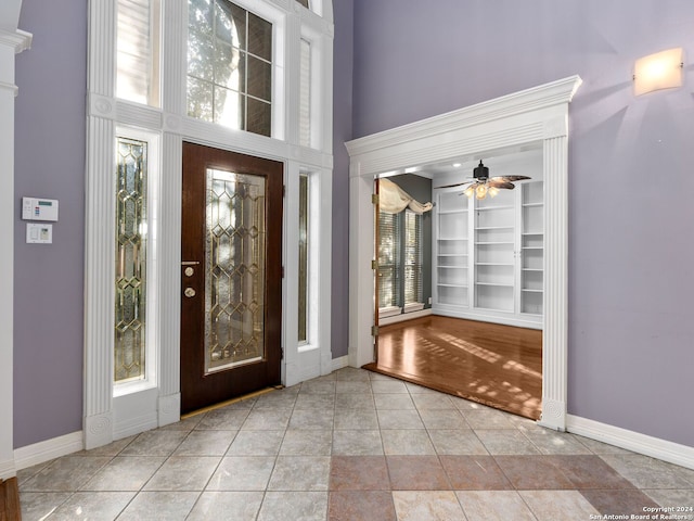 tiled foyer entrance with ceiling fan and a high ceiling