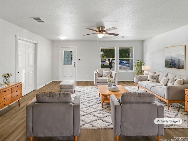 living room featuring hardwood / wood-style flooring, ceiling fan, and a textured ceiling