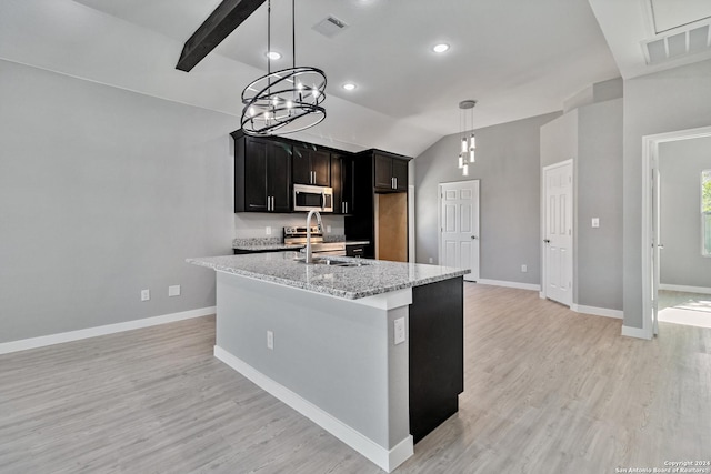 kitchen featuring light stone countertops, appliances with stainless steel finishes, sink, lofted ceiling with beams, and light hardwood / wood-style floors