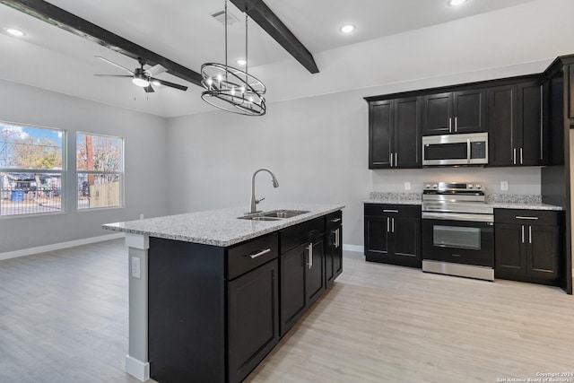 kitchen with a center island with sink, sink, light hardwood / wood-style flooring, beamed ceiling, and stainless steel appliances