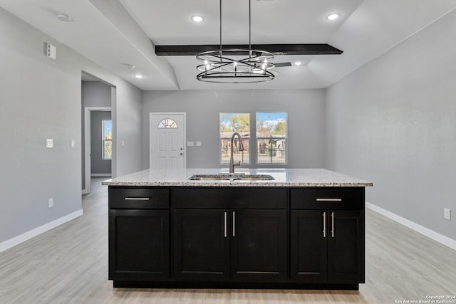 kitchen with an inviting chandelier, a center island with sink, sink, vaulted ceiling with beams, and light hardwood / wood-style floors