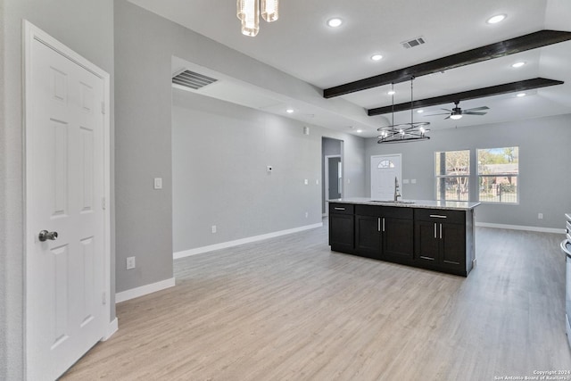 kitchen featuring a kitchen island with sink, beamed ceiling, pendant lighting, and light hardwood / wood-style floors