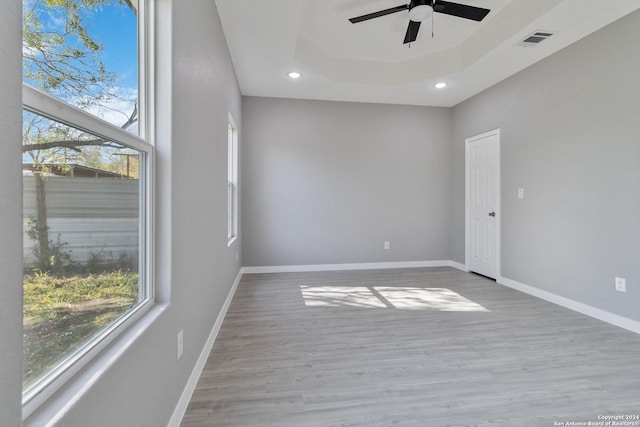 empty room featuring ceiling fan, a raised ceiling, and light wood-type flooring