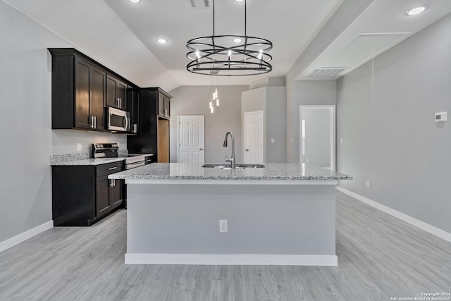 kitchen with light stone countertops, sink, an island with sink, and stainless steel appliances