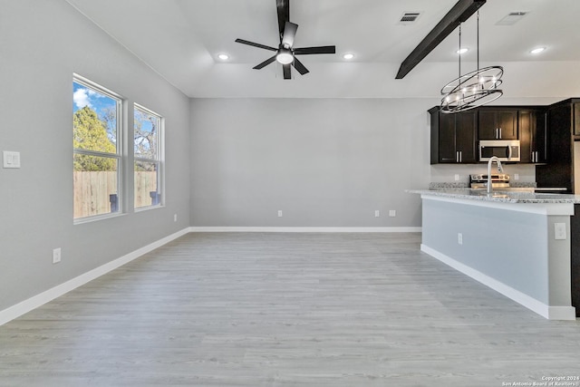 kitchen featuring ceiling fan with notable chandelier, light hardwood / wood-style floors, light stone counters, and stainless steel appliances