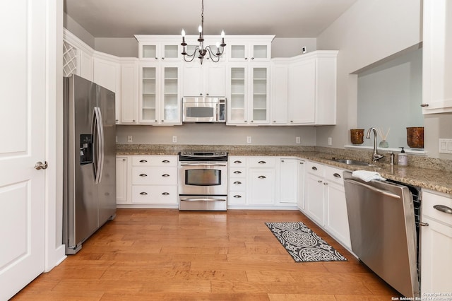 kitchen with white cabinets, light hardwood / wood-style floors, stainless steel appliances, and an inviting chandelier