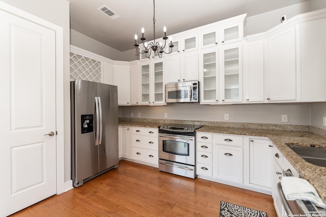 kitchen featuring light stone counters, a notable chandelier, light hardwood / wood-style floors, white cabinets, and appliances with stainless steel finishes