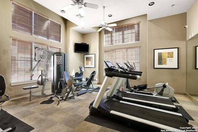 workout area featuring carpet flooring, ceiling fan, and a high ceiling