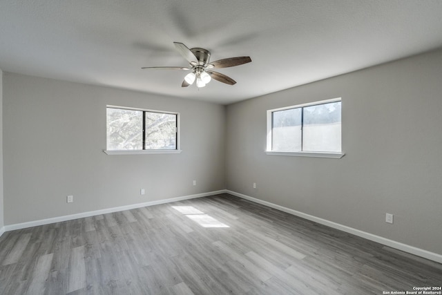 spare room featuring a wealth of natural light, light hardwood / wood-style flooring, ceiling fan, and a textured ceiling