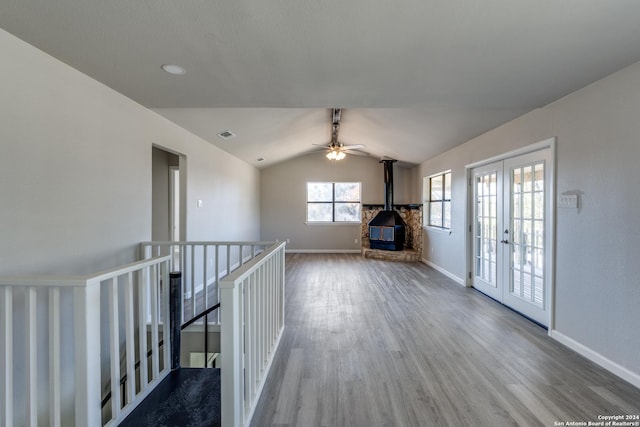 interior space featuring lofted ceiling, a wood stove, french doors, ceiling fan, and wood-type flooring