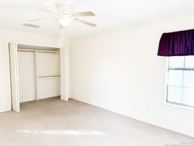 unfurnished bedroom with ceiling fan, light carpet, and a closet