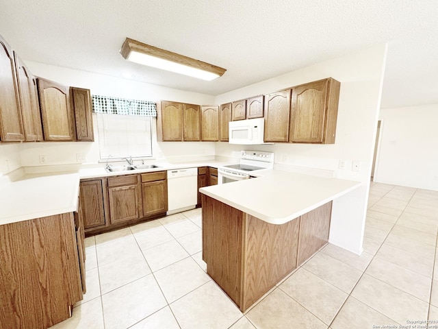 kitchen featuring kitchen peninsula, a kitchen breakfast bar, a textured ceiling, white appliances, and sink