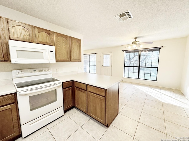 kitchen featuring a textured ceiling, plenty of natural light, white appliances, and kitchen peninsula