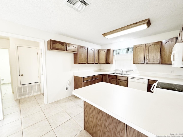 kitchen featuring kitchen peninsula, light tile patterned flooring, white appliances, and a textured ceiling