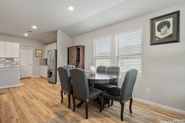 dining area featuring light wood-type flooring and vaulted ceiling