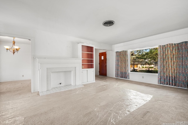 unfurnished living room with a tile fireplace, light colored carpet, and an inviting chandelier