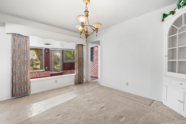 carpeted spare room featuring a notable chandelier