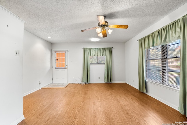 unfurnished room with a wealth of natural light, light hardwood / wood-style flooring, ceiling fan, and a textured ceiling