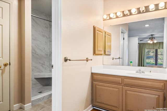 bathroom with a tile shower, vanity, and a textured ceiling