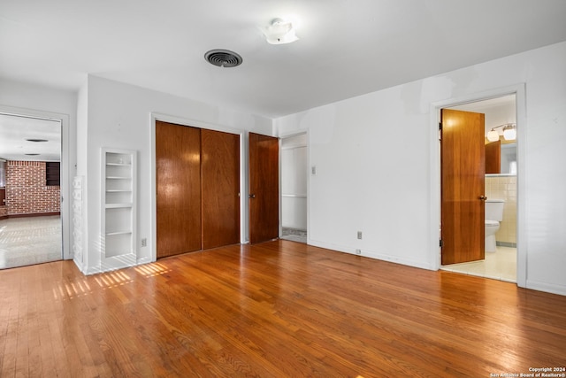 unfurnished bedroom featuring connected bathroom and light hardwood / wood-style flooring