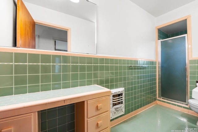 bathroom featuring heating unit, toilet, a shower with door, and tile walls