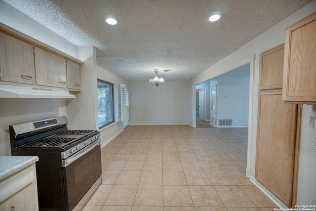 kitchen with hanging light fixtures, a textured ceiling, light brown cabinetry, light tile patterned flooring, and stainless steel range with gas stovetop