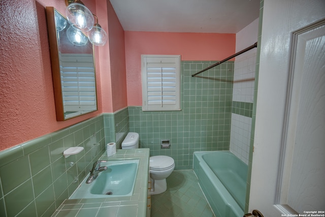 full bathroom with tiled shower / bath combo, toilet, tile walls, and sink