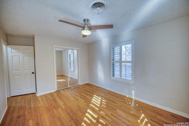 unfurnished bedroom featuring ceiling fan, a closet, a textured ceiling, and light wood-type flooring