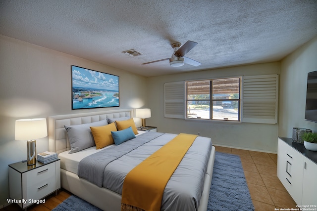 bedroom with ceiling fan, light tile patterned floors, and a textured ceiling