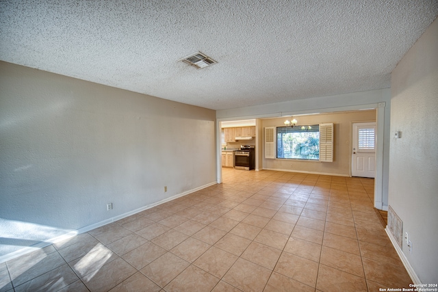 tiled empty room featuring a notable chandelier and a textured ceiling