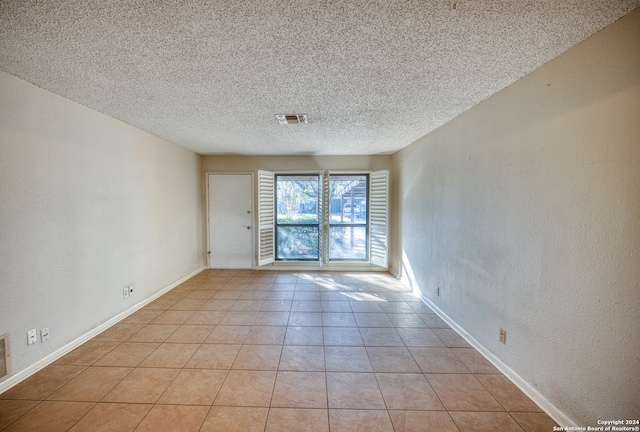 tiled empty room with a textured ceiling